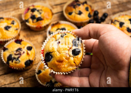 Hand holding muffins aux petits fruits première personne Banque D'Images