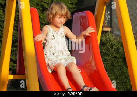 Peu de sixième année vieille fille sur l'aire de jeux toboggan avec la peur dans ses yeux Banque D'Images