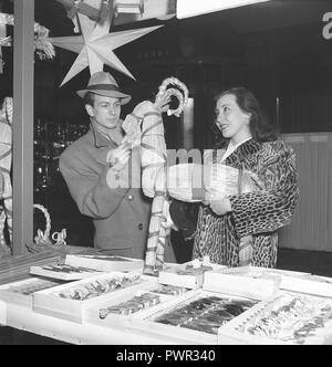 Noël dans les années 40. Un jeune couple est de visiter un marché de Noël et avons trouvé une paille de Noël fait main chèvre. Suède 1945. Kristofferson Photo ref L45-5 Banque D'Images