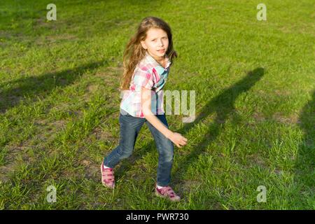 L'exécution de petite fille dans le parc, l'enfant s'amuse, jouer et courir sur la pelouse verte. Banque D'Images