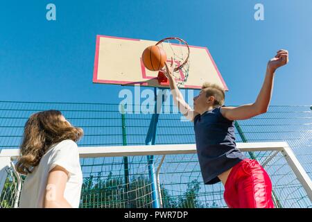 Match de basket-ball Streetball avec deux joueurs, les adolescents fille et garçon, matin sur un terrain de basket-ball. Banque D'Images