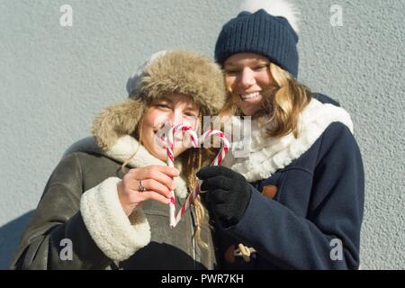 Happy smiling jolies adolescentes avec des cannes de Noël, des amies holding bonbons en forme de cœur, les gens positifs et l'amitié s Banque D'Images