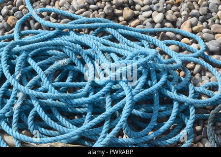 En bleu enroulée corde posée sur une plage de galets Banque D'Images