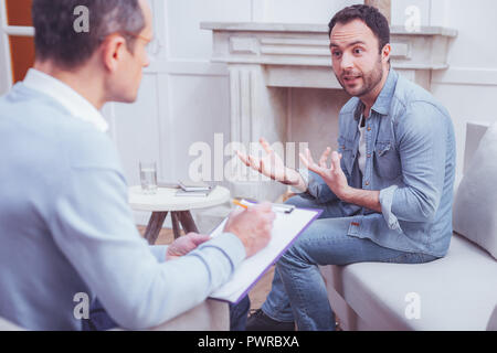 Homme barbu excité expliquant ses problèmes de psychiatre Banque D'Images
