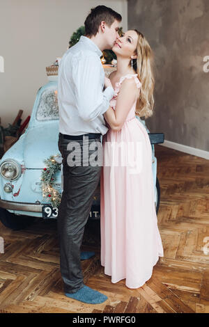 Belle mari embrassant belle blonde woman wearing robe rose. Banque D'Images