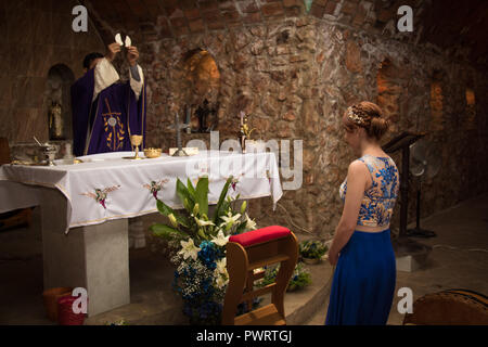 Fille en bleu robe dentelle recevant l'évangile dans l'église en pierre Banque D'Images