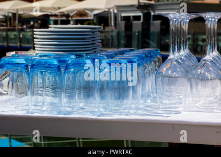 Verres teintés bleu et verres à vin avec des plaques empilées dans un restaurant sur le port de plaisance de Vilamoura, Portugal Banque D'Images