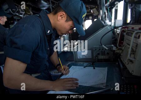 Océan Pacifique (20 juin 2017) Ensign Jeffrey Alcantara, de Glendale, en Arizona, parcelles un contact alors que l'article de veille sur la passerelle à bord de la classe Ticonderoga croiseur lance-missiles USS Princeton (CG 59). Princeton est en cours dans le cadre du Groupe aéronaval Nimitz en fonction d'un programme de déploiement de l'ouest du Pacifique et l'Océan Indien. ( Banque D'Images