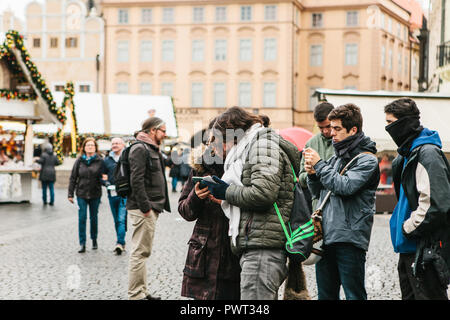 Prague, le 25 décembre 2017 : un jeune couple de touristes regarde une carte sur un téléphone cellulaire sur la place principale de Prague pendant les vacances de Noël. Banque D'Images