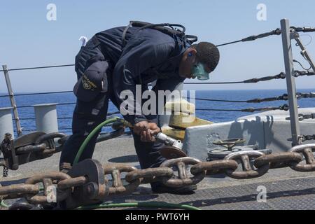 Mer Méditerranée (30 juin 2017) - Maître de Manœuvre Seaman Apprentice Tariq Doolin procède à la préservation l'entretien sur la chaîne d'ancre à bord de la classe Arleigh Burke destroyer lance-missiles USS Carney (DDG 64) dans la mer Méditerranée le 30 juin 2017. Carney, l'avant-déployé à Rota, Espagne, effectue actuellement sa troisième patrouille dans la sixième flotte américaine zone d'opérations à l'appui de la sécurité nationale des États-Unis en Europe. ( Banque D'Images