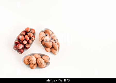 Plaques avec amandes, noisettes et noix, sur fond de toile blanche. Banque D'Images