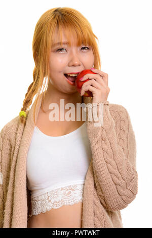 Young happy Asian woman smiling and eating red apple Banque D'Images