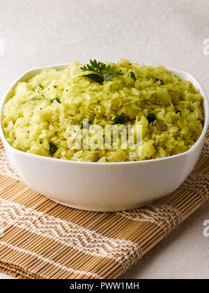 BATATA POHA fabriqués à partir de flocons de riz soufflé, de la pomme de terre et oignons. servi avec de la chaux et piments verts Banque D'Images