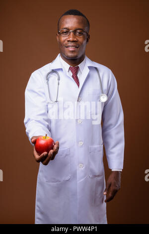 Portrait de jeune homme africain médecin contre fond brun Banque D'Images