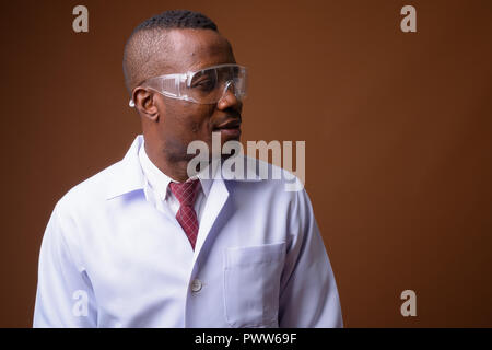 Portrait de jeune homme africain médecin contre fond brun Banque D'Images