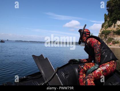 Un nageur de sécurité continue d'oeil sur une équipe du 3e Bataillon, 1st Special Forces Group (Airborne) lors d'un concours organisé pendant la semaine 'ambulance' sur Joint Base Lewis-McChord, dans l'État de Washington, le 28 juin. La semaine Dragon comprenait les opérations aéroportées, opérations maritimes, voies de patrouille, un shoot de stress, et les évaluations médicales de test au niveau du bataillon. Banque D'Images