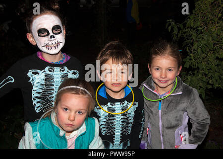 Ressemble à quatre frères et sœurs dehors pour une nuit de Halloween trucs ou traite avec les deux plus anciens vêtus de costumes squelette. St Paul Minnesota MN USA Banque D'Images