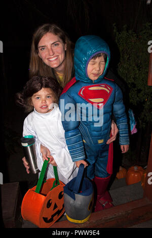 Maman apporte la Princesse Leia en costume tenant un panier de bonbons à la citrouille et d'un strabisme Superman pour l'Halloween des trucs ou des friandises. St Paul Minnesota MN USA Banque D'Images