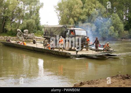 Des soldats américains affectés à l'Escadron d'artillerie, 2e régiment de cavalerie légère moyenne ont leur véhicule tactique et M777 transportés sur le fleuve Mosoni-Duna à Györ, Hongrie par un pont mobile lors de l'exercice Szentes Ax 17 Juillet 4, 2017. Le pont est exploité par les ingénieurs du 37e Régiment du génie, de la Force de défense hongroise et 837ème bataillon du génie de la Brigade, U.S. Army National Guard de Wooster, Ohio. L'exercice national hongrois a lieu le 26 Juin-Juillet 7 pour permettre aux tuteurs de sabre 17 en procédant à l'eau et de raccordement tactique pour opérations de passage 2CR la liberté de se déplacer Banque D'Images