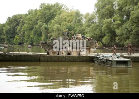 Soldats affectés au 1er Escadron, 2e régiment de cavalerie, l'armée américaine de conduire leur véhicule de combat Stryker sur la rivière Mosoni-Duna à Györ, Hongrie sur un pont flottant PMP pendant l'exercice Szentes Ax 17 Juillet 4, 2017. Le pont a été mis en place par des ingénieurs à partir de la 37e Régiment du génie, de la Force de défense hongroise et 837ème bataillon du génie de la Brigade, U.S. Army National Guard de Wooster, Ohio. L'exercice national hongrois a lieu le 26 Juin-Juillet 7 pour permettre aux tuteurs de sabre 17 en procédant à l'eau et de raccordement tactique pour opérations de passage 2CR la liberté de mouvement à partir de la station d'accueil en Hongrie et Banque D'Images