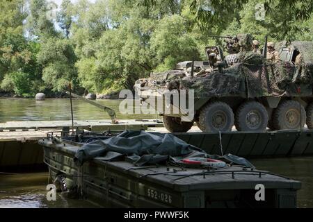 Soldats affectés au 1er Escadron, 2e régiment de cavalerie, l'armée américaine de conduire leur véhicule de combat Stryker sur la rivière Mosoni-Duna à Györ, Hongrie sur un pont flottant PMP pendant l'exercice Szentes Ax 17 Juillet 4, 2017. Le pont a été mis en place par des ingénieurs à partir de la 37e Régiment du génie, de la Force de défense hongroise et 837ème bataillon du génie de la Brigade, U.S. Army National Guard de Wooster, Ohio. L'exercice national hongrois a lieu le 26 Juin-Juillet 7 pour permettre aux tuteurs de sabre 17 en procédant à l'eau et de raccordement tactique pour opérations de passage 2CR la liberté de mouvement à partir de la station d'accueil en Hongrie et Banque D'Images