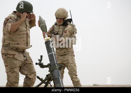 Un soldat de l'armée iraquienne charge un mortier de 120 mm pendant la formation de tir indirect dirigé par l'armée portugaise à la gamme Besmaya Juillet 5, 2017 complexe. Cette formation fait partie de la Force opérationnelle interarmées combinée globale - Fonctionnement résoudre inhérent à la mission de renforcer les capacités des partenaires qui se concentre sur la formation et de l'amélioration de la capacité des forces des combats en partenariat avec ISIS. Les GFIM-OIR est la Coalition mondiale pour vaincre ISIS en Iraq et en Syrie. Banque D'Images