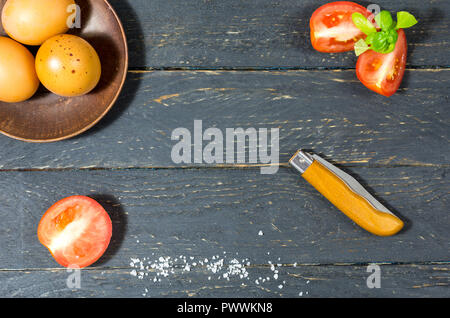 Les légumes et les oeufs de poule sur un fond de bois sombre. Le couteau est plié. Banque D'Images