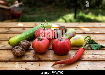 Les légumes bio et les noix d'un petit jardin sur une table en bois rustique - Tomates, Concombres, Poivrons, paprika, piment Banque D'Images