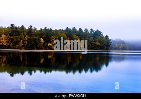 Couleurs d'automne à Walden Pond reflétant sur l'eau avec des nuages bas à l'arrière-plan Banque D'Images