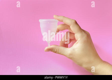Close up of woman hand holding coupelle menstruelle sur fond rose. Le concept de la santé des femmes, zéro waste alternatives Banque D'Images