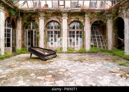 Grand piano brisé gisant sur le sol dans la cour d'un palais abandonné en Pologne. Banque D'Images