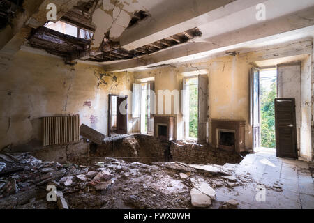 Vue intérieure d'une villa abandonnée avec des trous dans le sol en raison d'un tremblement de terre en Italie. Banque D'Images