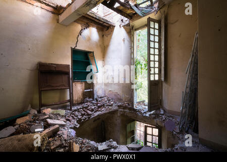 Vue intérieure d'une villa abandonnée avec des trous dans le sol en raison d'un tremblement de terre en Italie. Banque D'Images