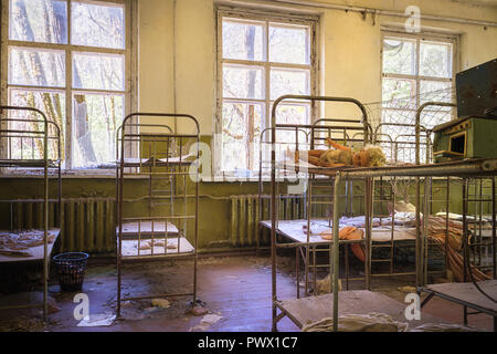 Vue intérieure d'une chambre avec lit dans une école abandonnée à Tchernobyl, en Ukraine. Banque D'Images