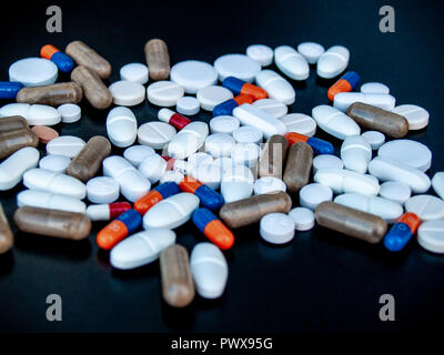 Comprimés de différentes tailles, formes et couleurs sur fond noir. Concept de santé Banque D'Images