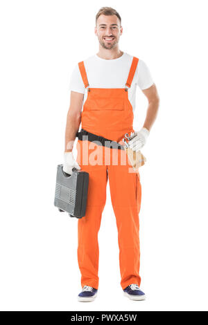 Smiling handsome auto mechanic en uniforme orange qui maintient la boîte à outils isolated on white Banque D'Images