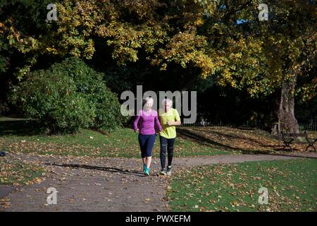 Un homme d'âge moyen et la femme par jog Pavilion Gardens à Buxton, Derbyshire, Royaume-Uni Banque D'Images