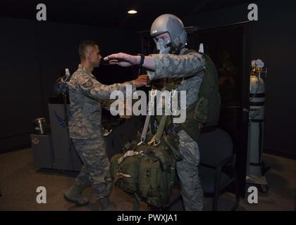 Tech. Le Sgt. Oscar Pena, 92e technicien en médecine aérospatiale, se déplace pour aider un membre de la 1re classe Jeff Eisberg, 22e Groupe d'entraînement de résistance et de survie Evasion Evasion spécialiste, au cours d'un dispositif de respiration d'oxygène réduite 26 juin 2017 simulation, à Fairchild Air Force Base, à Washington. Les pilotes, l'équipage et des parachutistes sont formés pour sensibiliser leur bras gauche pour signaler qu'ils ont besoin d'aide quand on vit les effets de l'hypoxie. Banque D'Images