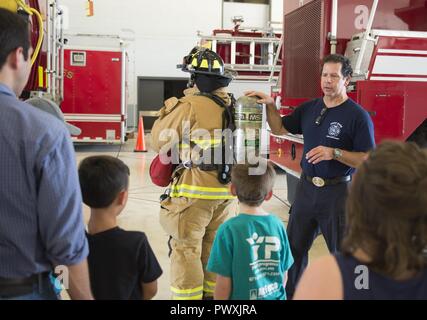 Jeffery Pardo (à gauche), 502e Escadron de génie civil pompier, porte son équipement de protection incendie que Michael Martinez, 502e ces pompier, parle des différents équipements pour les enfants de l'ABA au cours d'une vibrante Solutions Open House tour de la Caserne 2 Juin 23, 2017, at Joint Base San Antonio-Lackland, Texas. L'un des objectifs de l'accueil visite guidée est de rendre les enfants plus à l'aise avec les pompiers portent leur pleine vitesse pour ne pas être effrayé en cas d'urgence. Banque D'Images