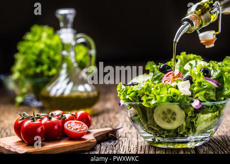 Salade de légumes Laitue Oignon tomates avec le fromage et les olives. Verser l'huile d'olive dans le bol de salade. Banque D'Images