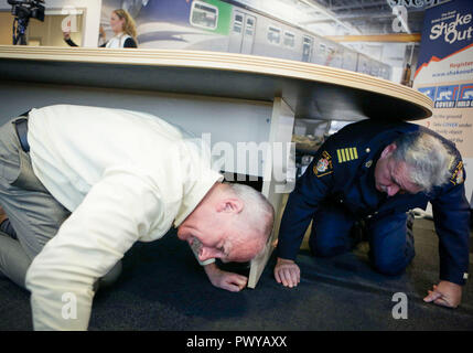 Vancouver, Canada. 18 Oct, 2018. Les gens se cache sous la table pendant la 'grande' Shakeout exercice séisme à Vancouver, Canada, le 18 octobre 2018. Sur 910 000 personnes ont participé à l'assemblée "grand bouleversement" exercice séisme en Colombie Britannique du Canada. Un exercice de simulation effectuée par Canada Line - Vancouver, sans conducteur de trains commandés par ordinateur, dans la pratique comment les opérateurs de transport et les résidents réagissent après le séisme d'alerte rapide question alerte. Credit : Liang Sen/Xinhua/Alamy Live News Banque D'Images