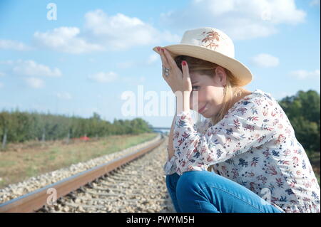 Une jeune femme blonde attendre pour locomotive, essayez d'arrêter le train Banque D'Images