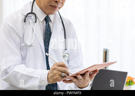 Libre senior Doctor using tablet en salle d'examen medical office. Banque D'Images