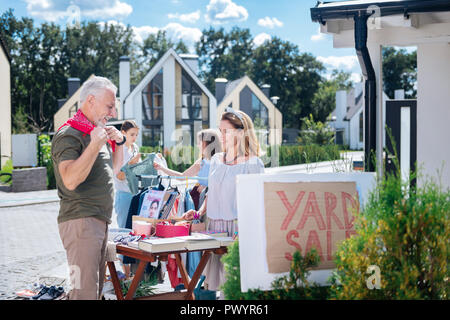 Cheerful mature barbu homme portant un pantalon beige de venir à yard sale Banque D'Images