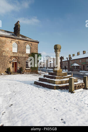 Hiver neige vue de la tête de sanglier Hôtels à Ripley dans le Yorkshire du Nord, avec la croix et les stocks du marché en face de l'hôtel Banque D'Images