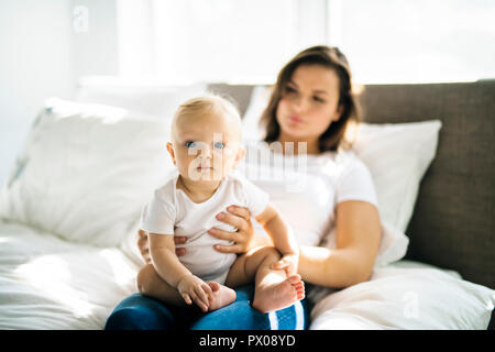 Mère avec bébé sur le lit après avoir bon temps Banque D'Images