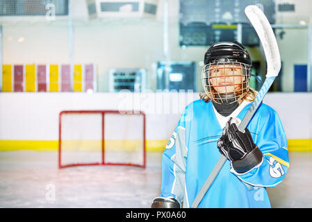 Portrait of teenage girl, joueur de hockey sur glace, posant avec un bâton sur la patinoire Banque D'Images