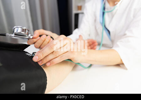 Une femme médecin la mesure de la pression artérielle d'un homme dans un bureau de médecins. Banque D'Images