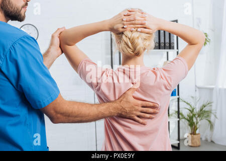 Cropped shot de kinésithérapeute faisant massage pour femme sur la table de massage à l'hôpital Banque D'Images