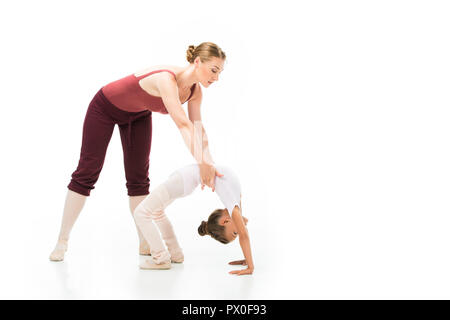 Female trainer holding petit enfant alors qu'elle fait de la gymnastique bridge isolé sur fond blanc Banque D'Images